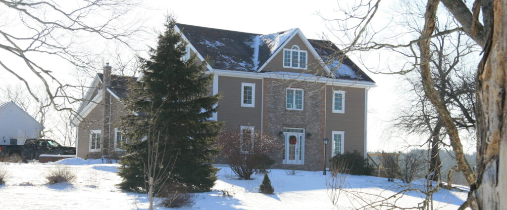 A light brown 2.5 storey historic home on a snowy hill.