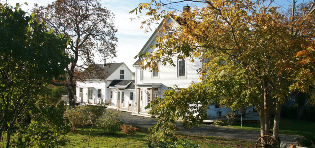 A white historic building surrounded by fall leaves.