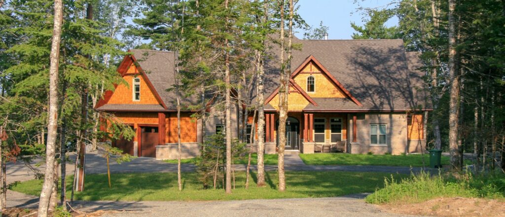 A light brown natural wood sided home with red trim sits among the trees.