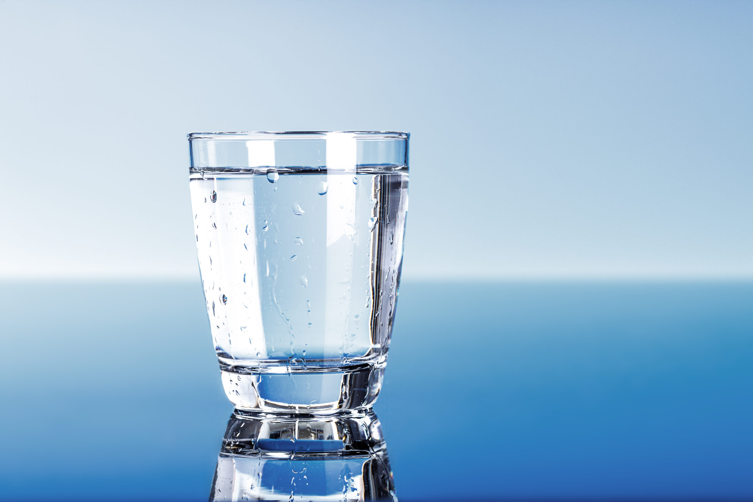 a glass of drinking water with a blue background