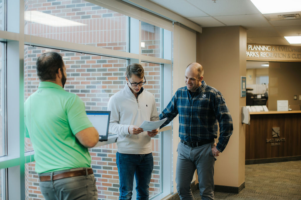 a group of staff members chat and look at a report by a window