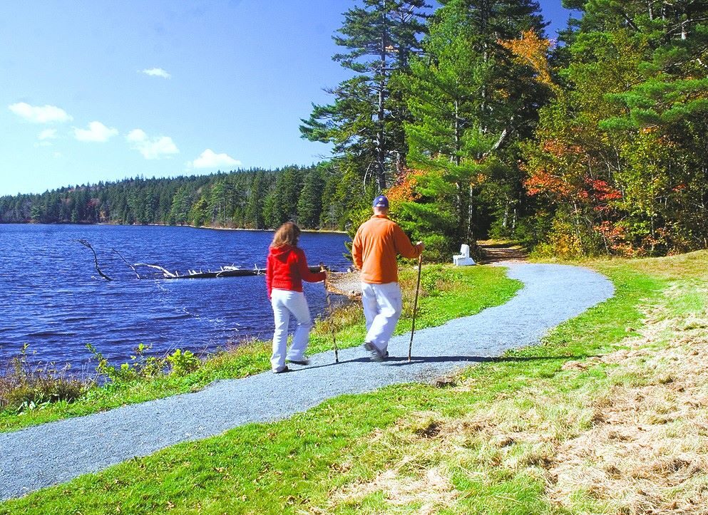 a couple walking on a trail by a lake on a sunny day