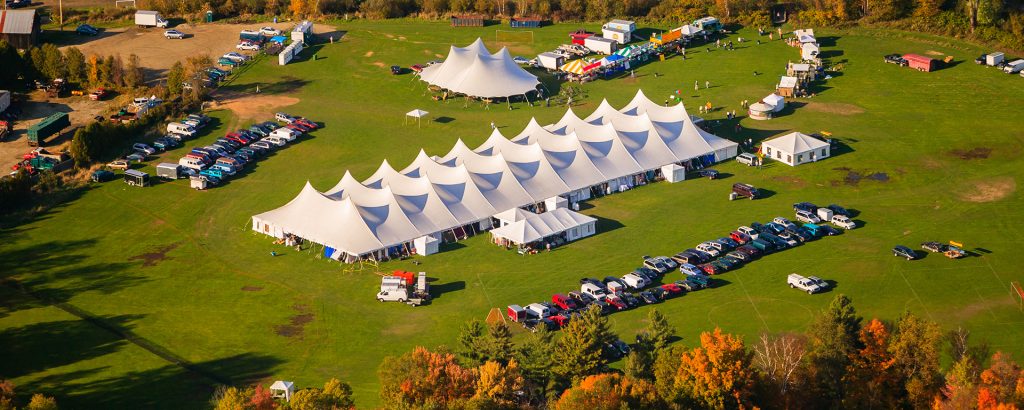 an aerial image of a large white event tent with cars parked around it