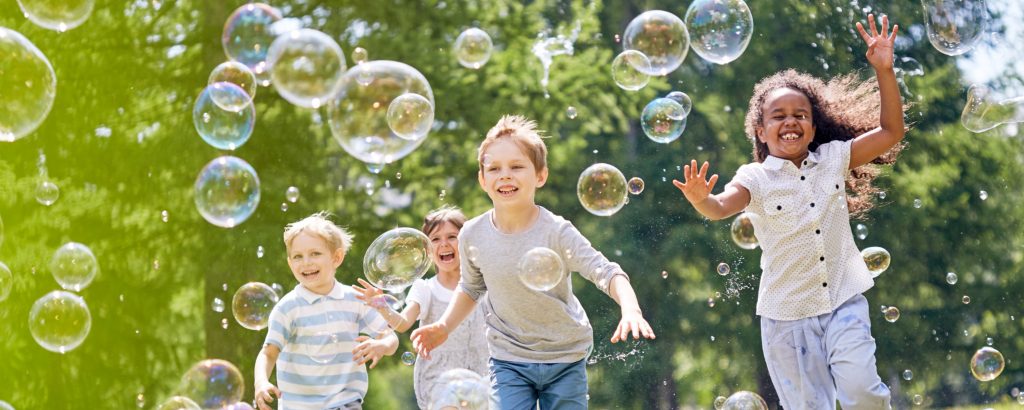 group of children chasing bubbles in the park