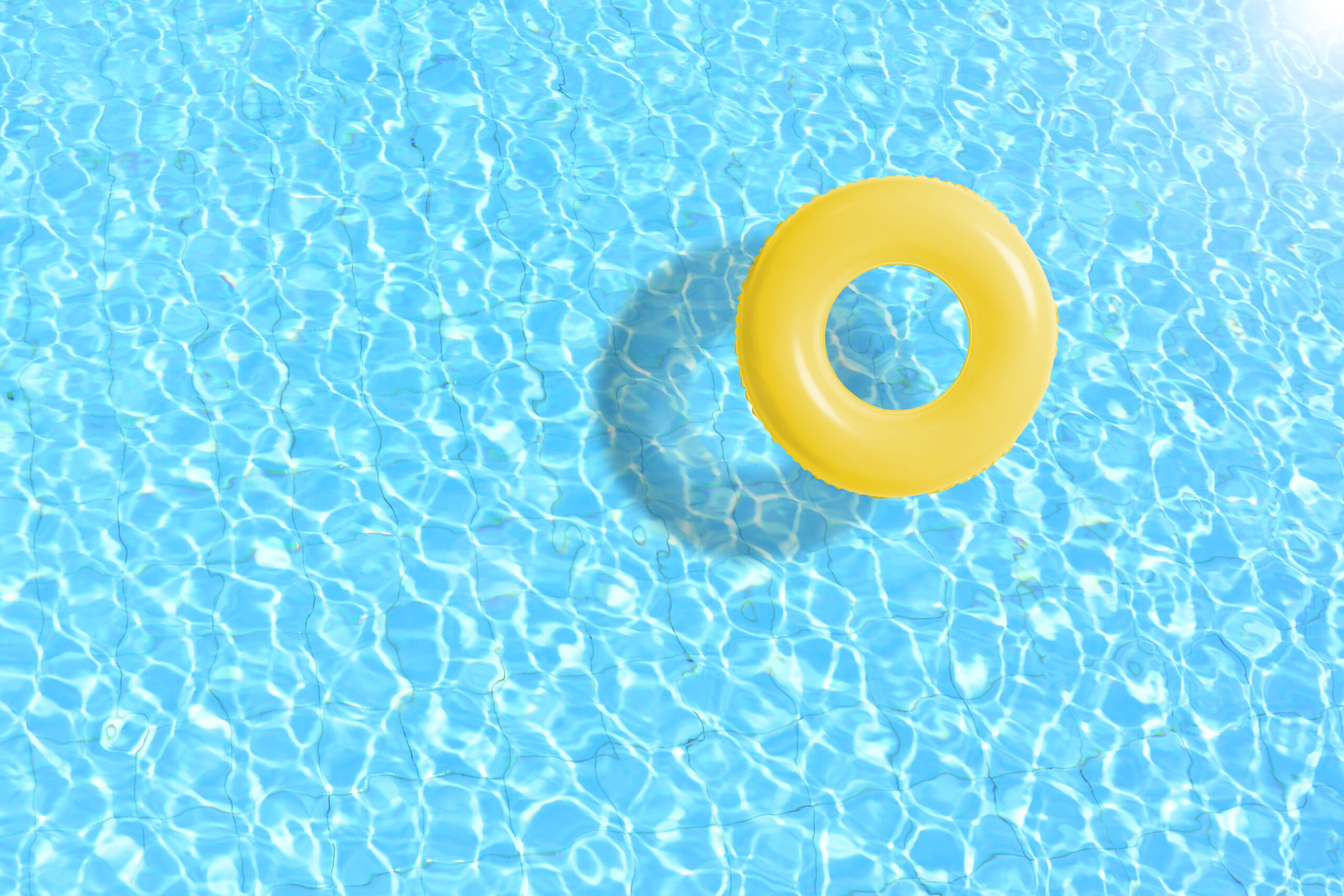 yellow swimming pool ring floats in blue water.
