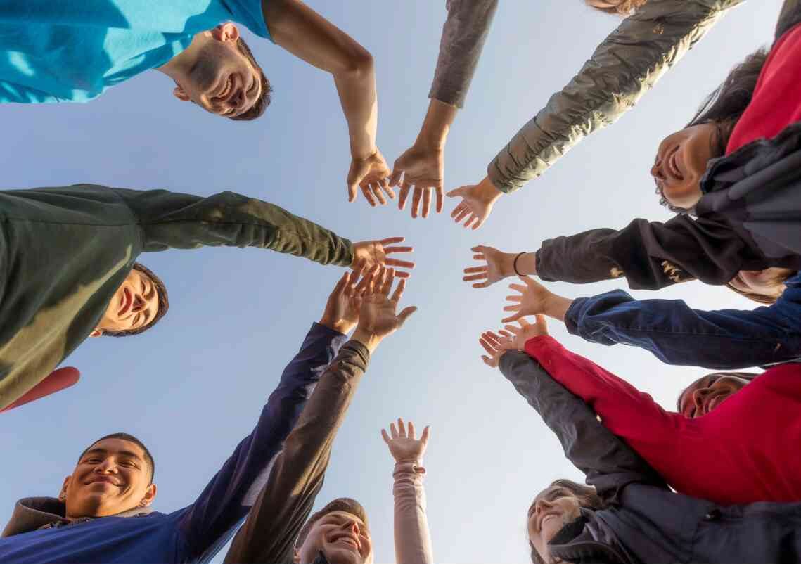 image shot from below a group of people putting their hands in a circle for a cheer