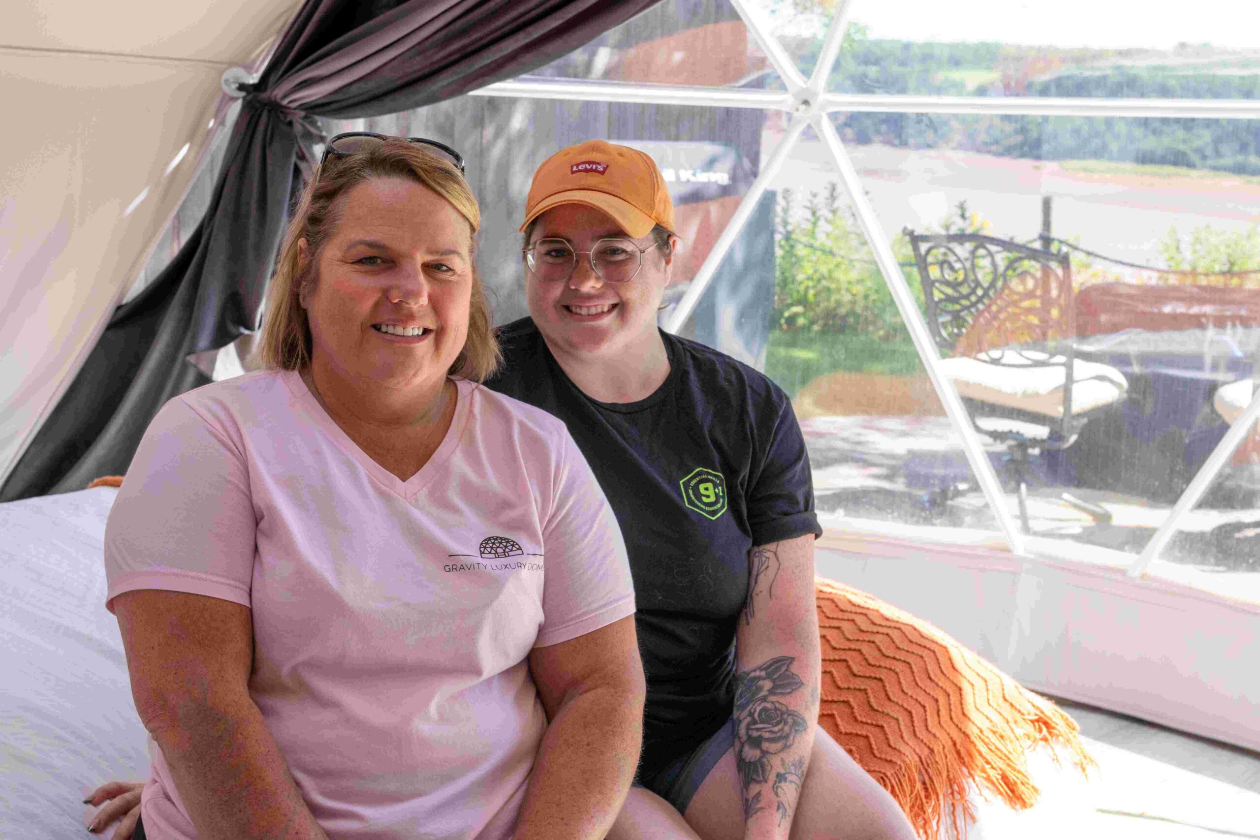 Mother and daughter owner-operators of Gravity Luxury Domes sit inside one of their glamping domes.