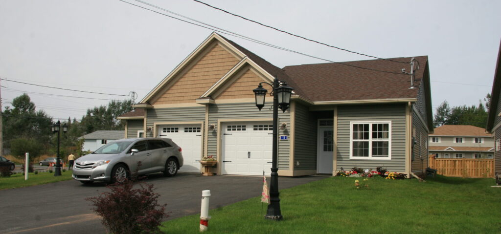 A duplex home with olive green siding and light brown trim.