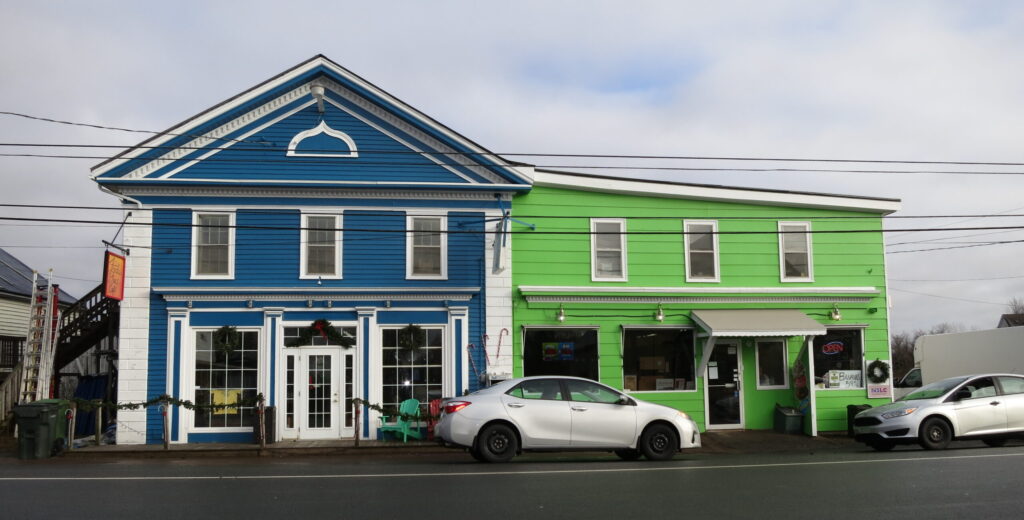 A historic general store with fresh blue and green paint with white trim.