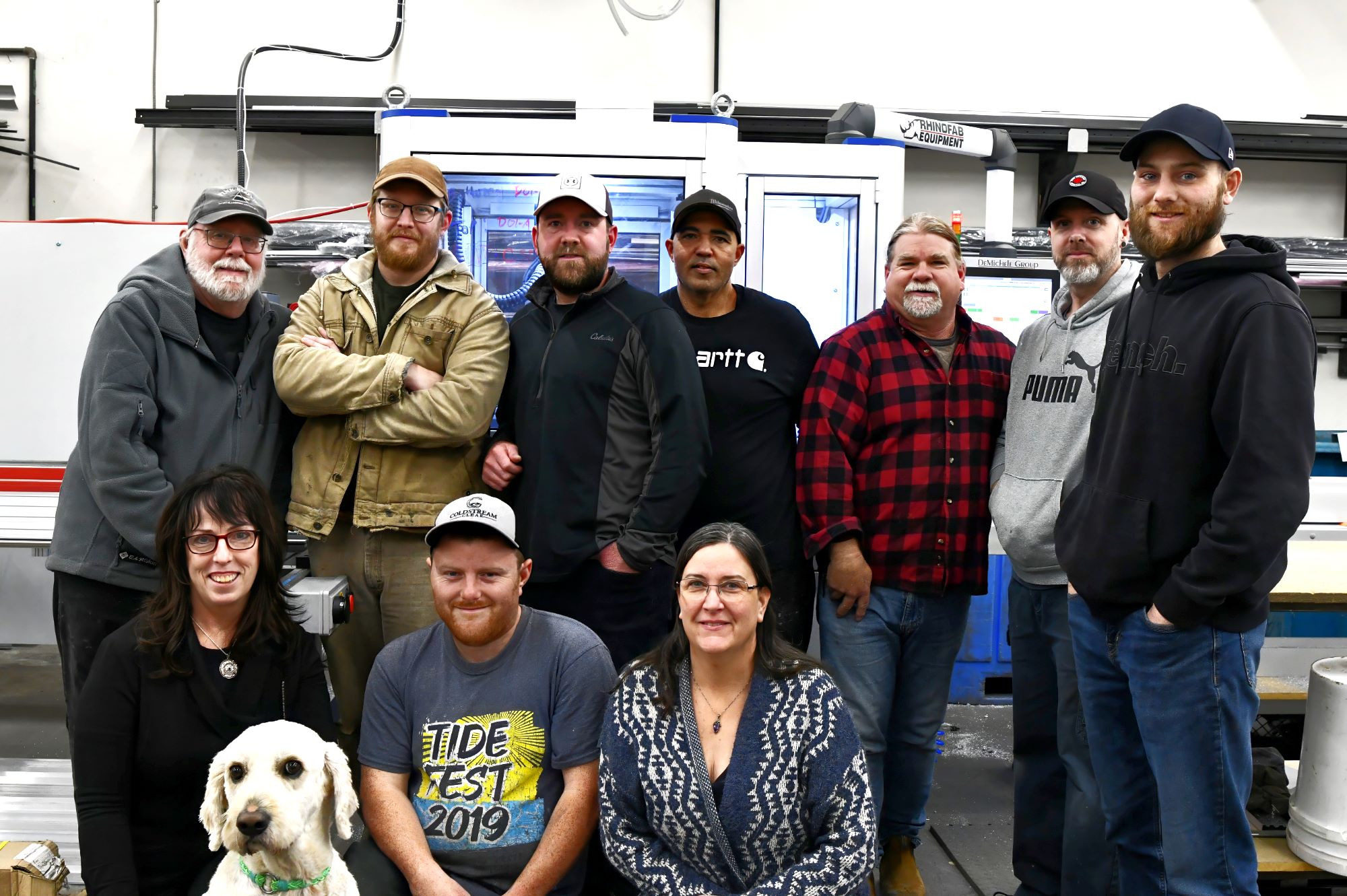 group of people and a dog pose in front of glass and aluminum equipment