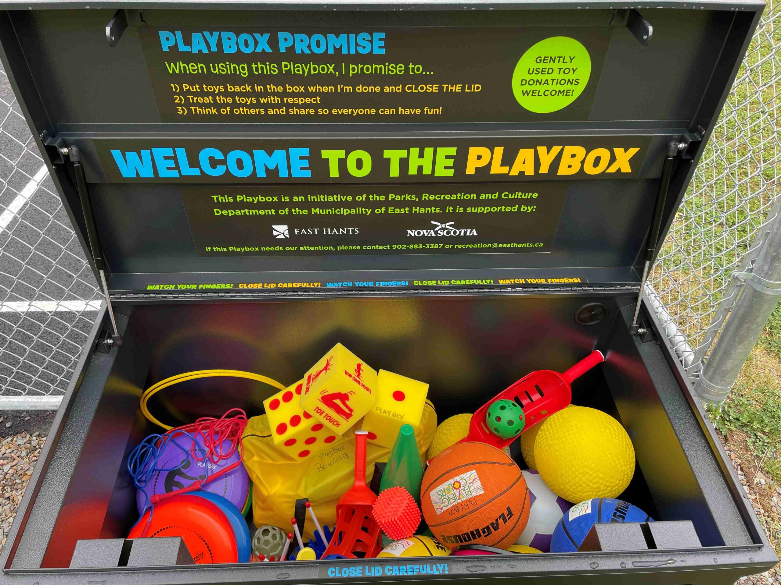 A large black box with colourful decals filled with outdoor toys