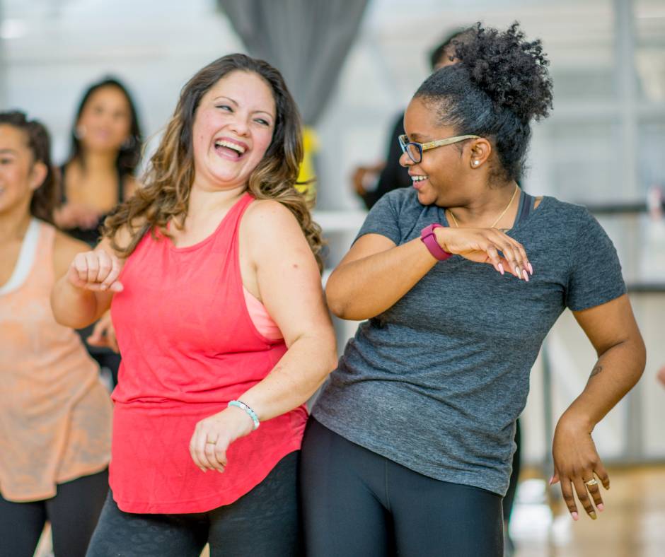 Two women bumping their hips together at a dance class