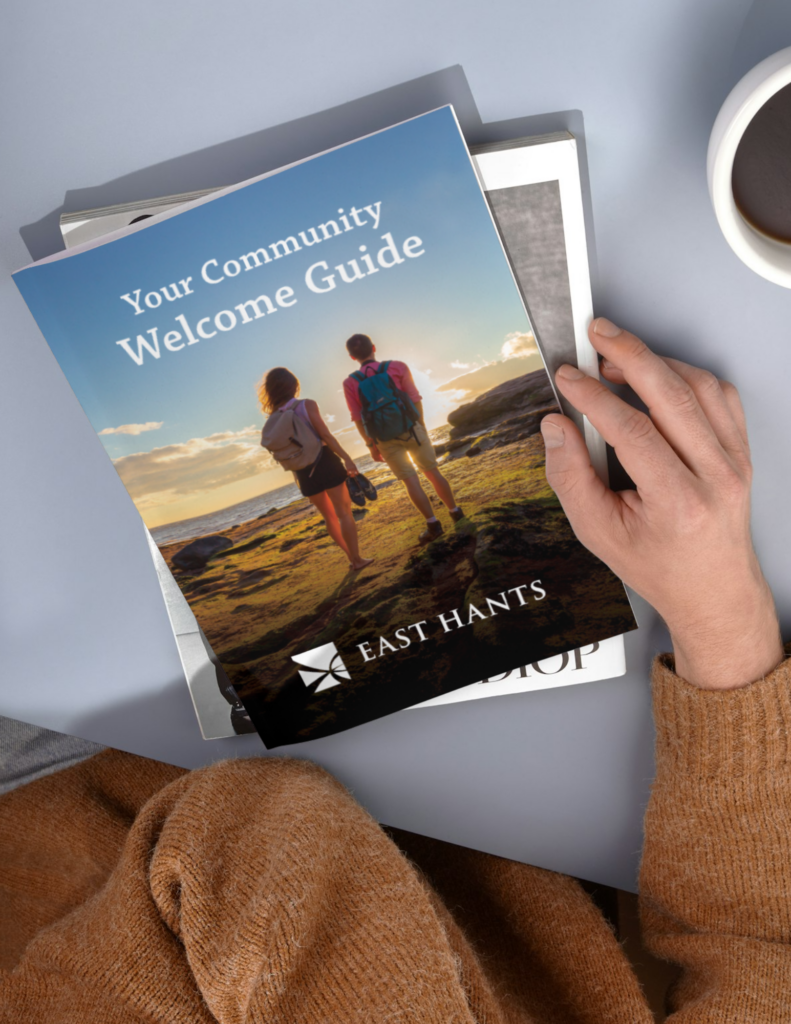 The East Hants Community Welcome Guide laying on a table with a hand holding it